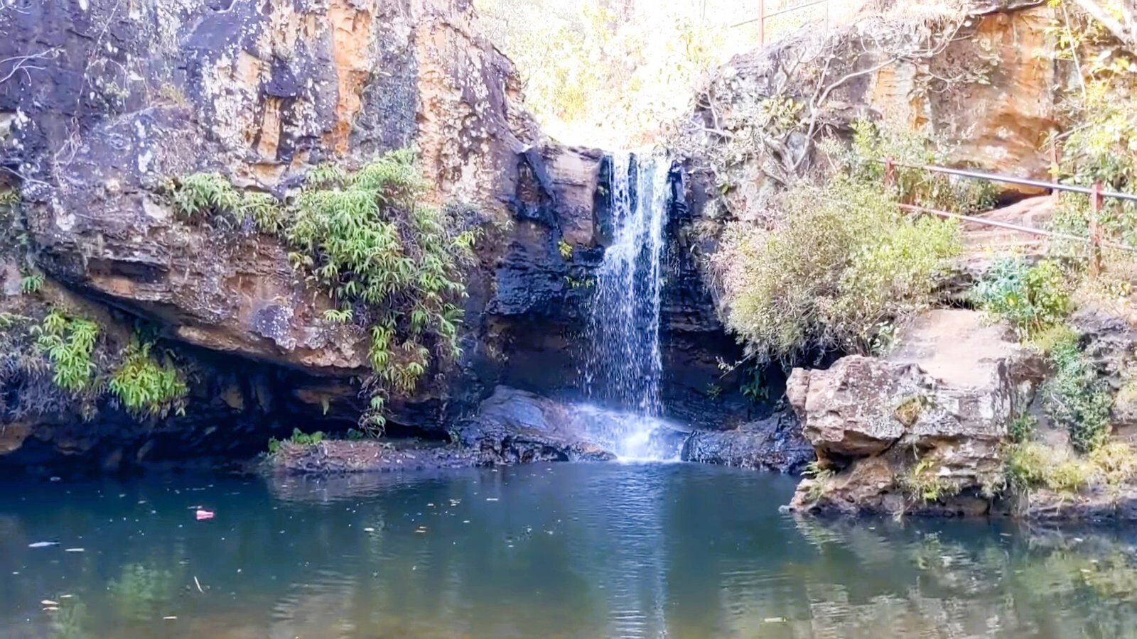 Waterfall falling into a clear pool between rocks in Pachmarhi